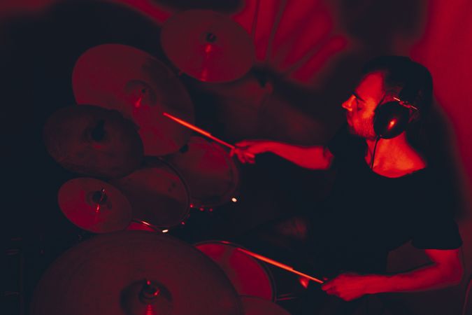 Man with drumsticks playing on drums in redness