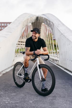 Cheerful man with bicycle standing on footbridge