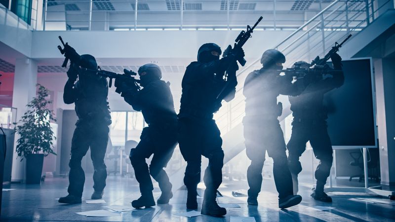 Masked Fireteam of Armed SWAT Police Officers Storm a Bright Seized Office Building with Desks and Computers.