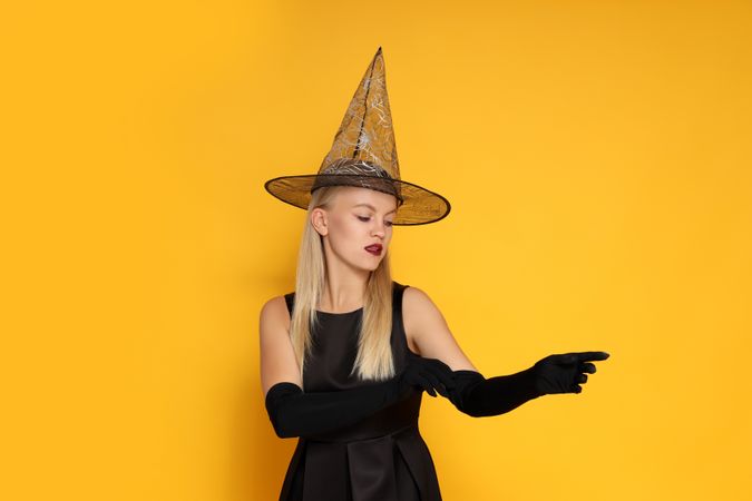 Concept of Halloween, young woman on yellow background