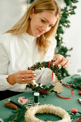 Woman making christmas wreath background lights