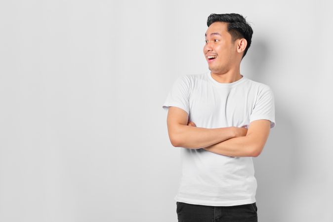 Surprised Asian male in grey studio looking away with copy space
