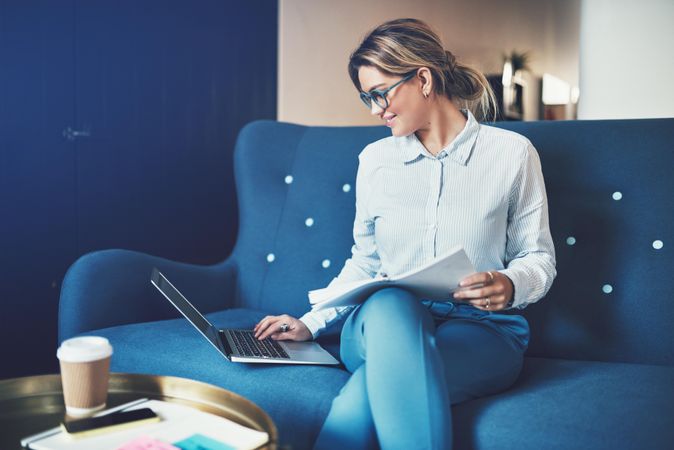 Female businesswoman in smart casual working on laptop on sofa