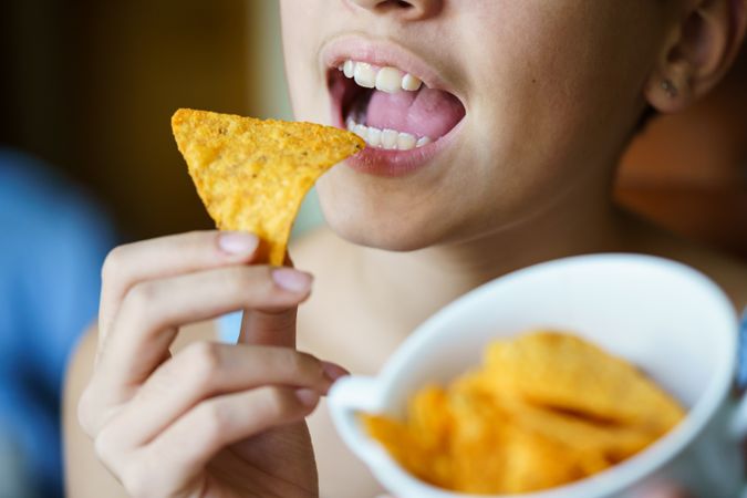 Teenage girl with bowl of nacho chips to snack on