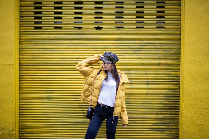 Trendy female standing near yellow wall on street