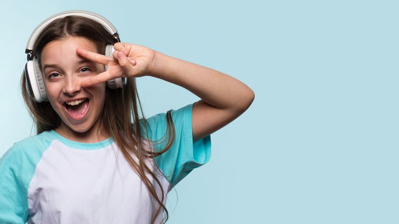 Happy girl flashing peace sign while wearing headphones