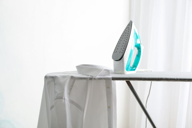 Iron and shirt on ironing board, space for text