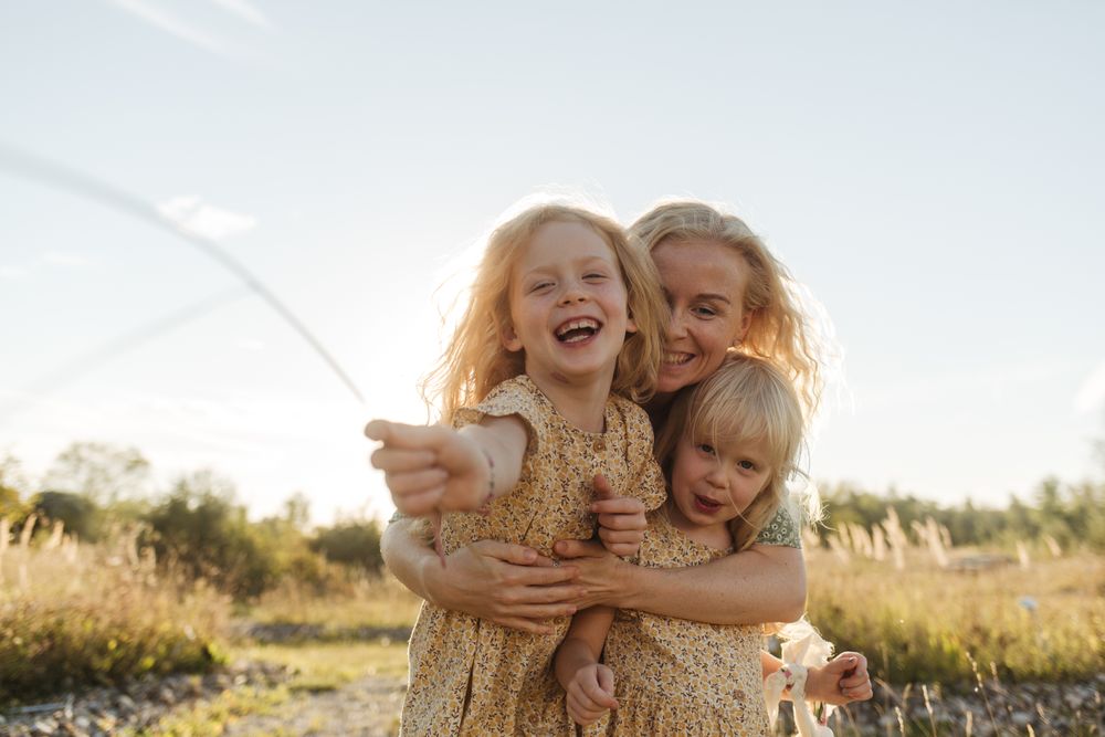 Cheerful mother embracing daughters in countryside