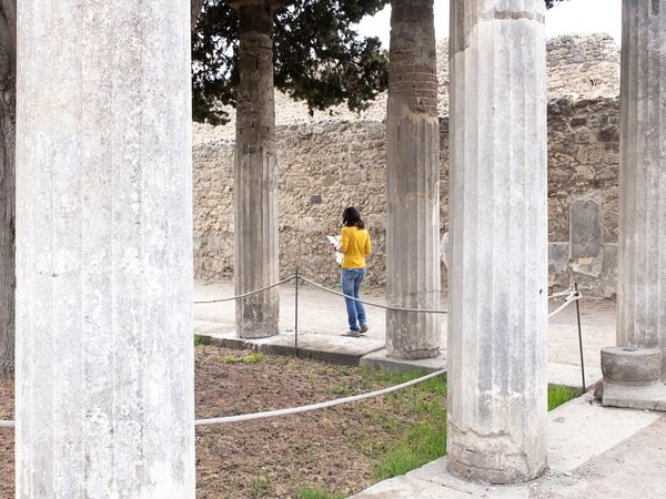 Woman in yellow clothes walking while exploring ancient ruins
