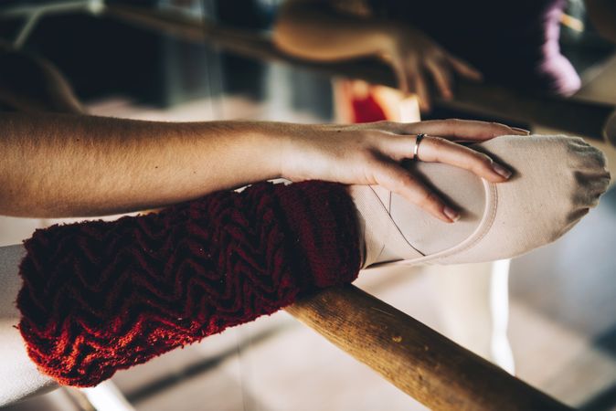 Crop shot of female leg in pointe shoe on barre stretching in studio.