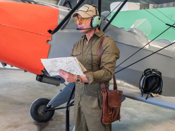 Pilot with map beside small plane