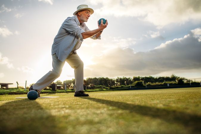 Low angle view of mature man in position to throw a boules