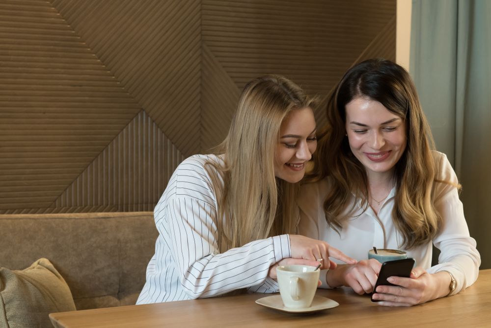 Young women looking at phone in cafe