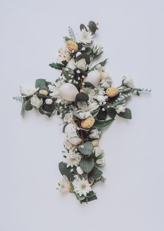 Easter layout with flowers and leaves in cross shape on light paper background