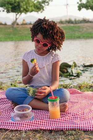 Girl eating broccoli in the park