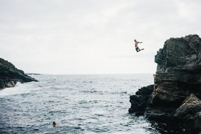 Side view of man leaping cliff jumping