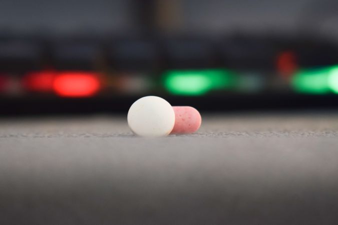 Two loose pills with bokeh lighting in background