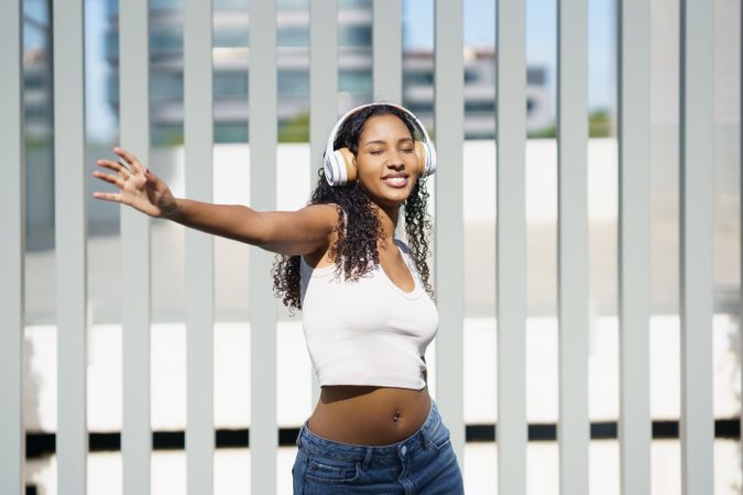 A Joyful Young Woman Dancing Outdoors While Wearing Stylish Headphones and Enjoying Life