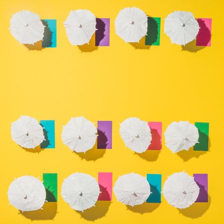 Pattern of sun umbrellas and multicolored towels in rows on yellow