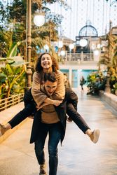 Man carrying happy girlfriend on back