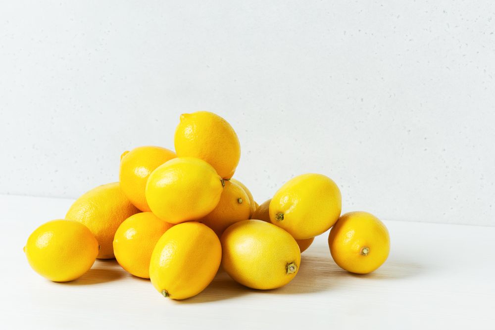 Pile of bright yellow lemons on light background