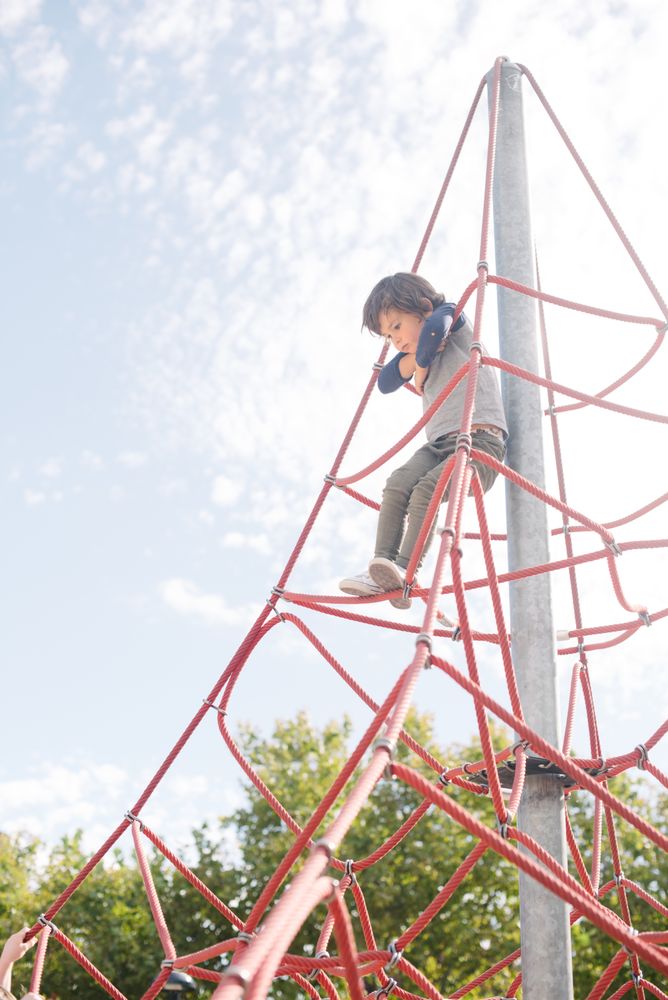 Boy on rope climbing net in sunlight