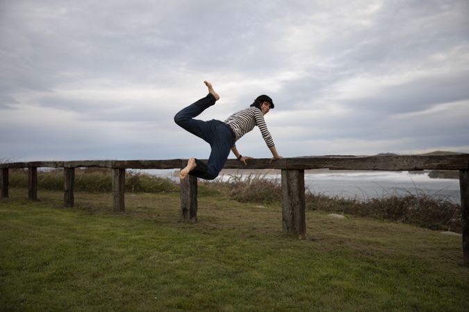 Woman jumping near bench on shore near water