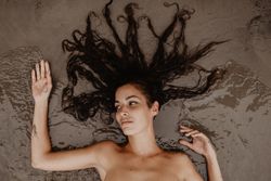 Young woman lying on wet sand