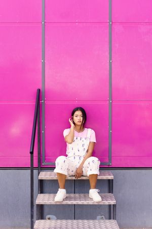 Woman in floral overalls sitting outside of bright pink trailer