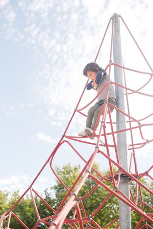 Boy on rope climbing net in sunlight