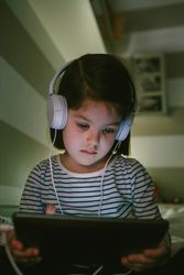 Girl with headphones looking at the tablet