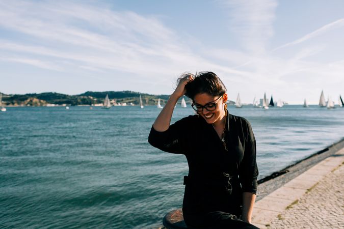 Stylish female holding hair and looking down on embankment