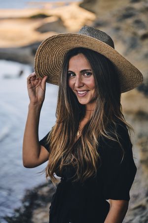 Cheerful woman holding hat in air