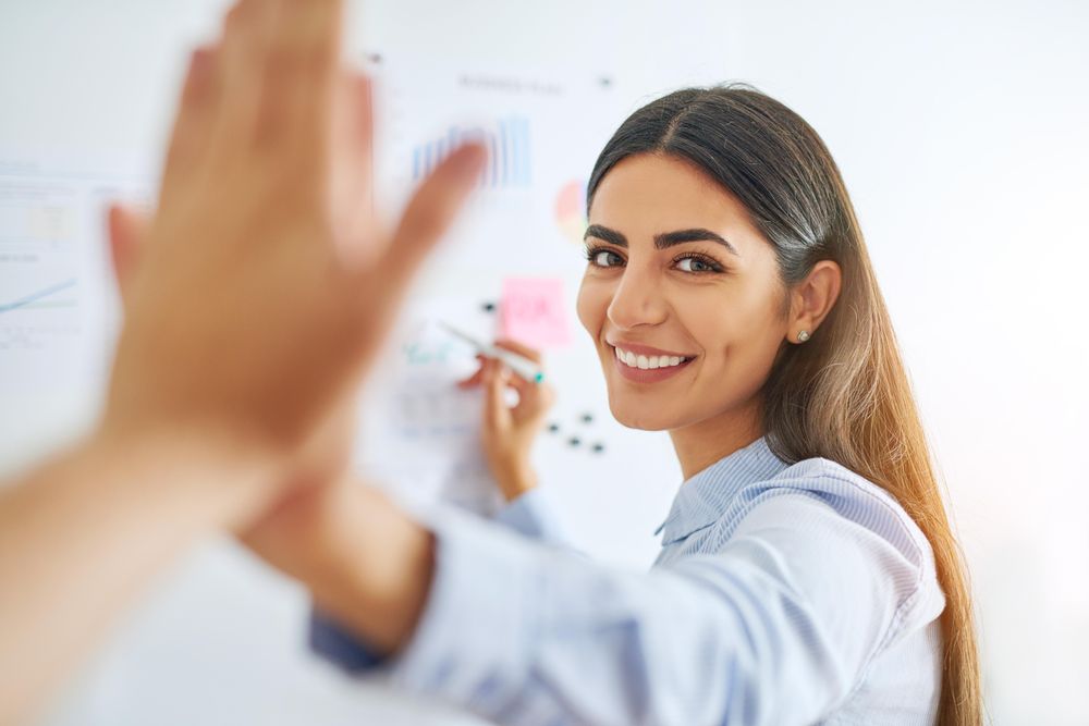 Smiling woman giving high five and looking at camera