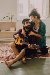 Cheerful couple playing guitar at home