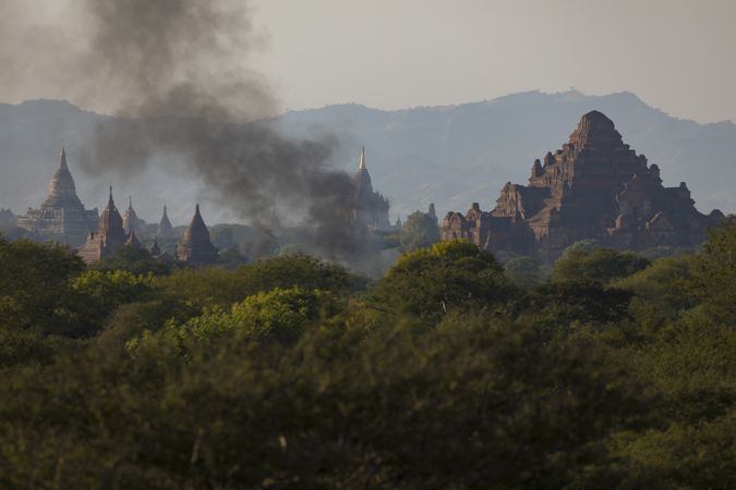 Smoke from a fire at sunset between the ancient Buddhist temples in the city of Bagan, Myanmar
