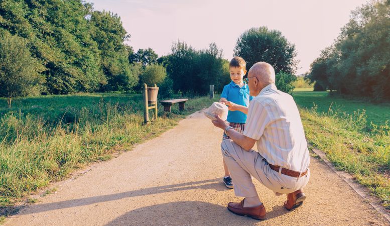 Grandfather showing his hat to grandchild outdoors