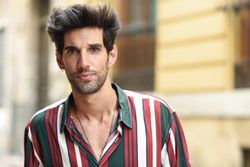 Portrait of serious dark haired man standing outside