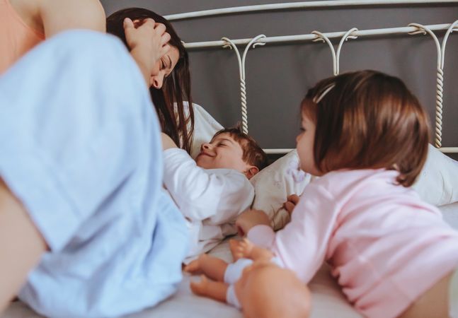 Portrait of happy mother and two children lying in bed on a relaxed morning