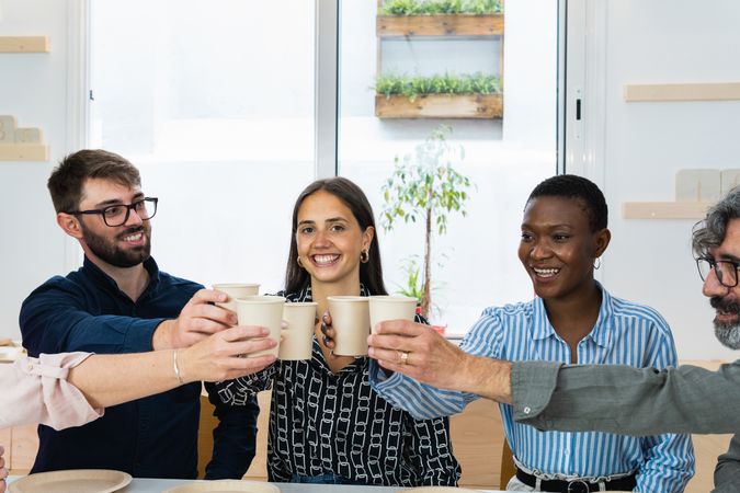Diverse colleagues having lunch together in kitchen of office