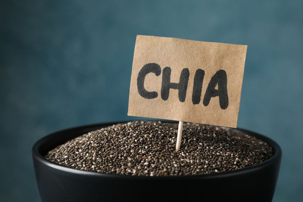 bowl and word Chia on wooden background, close up