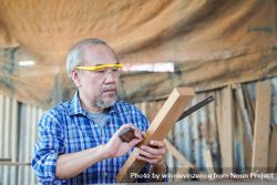 Asian male carpenter using ruler on wooden plank 4322zr