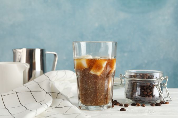Composition with glass of ice coffee on wooden table