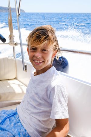 Happy preteen kid smiling at camera during cruise on yacht