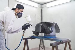 Man painting motorbike tank in workshop