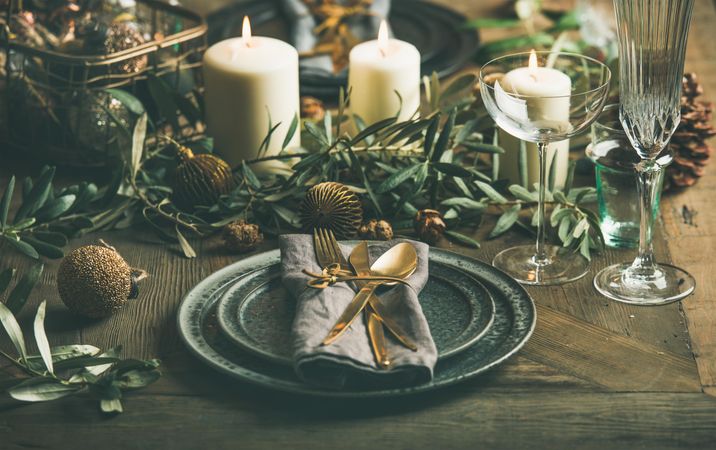 Holiday table setting with festive greens and candles on rustic wood table