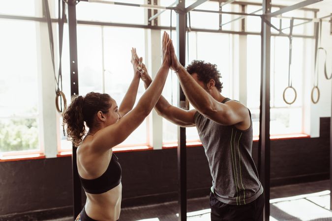 Fit man and woman high fiving at the gym
