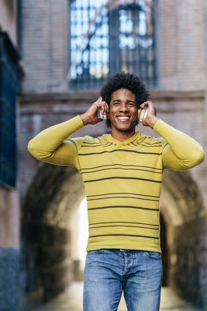 Man walking and smiling outside wearing headphones