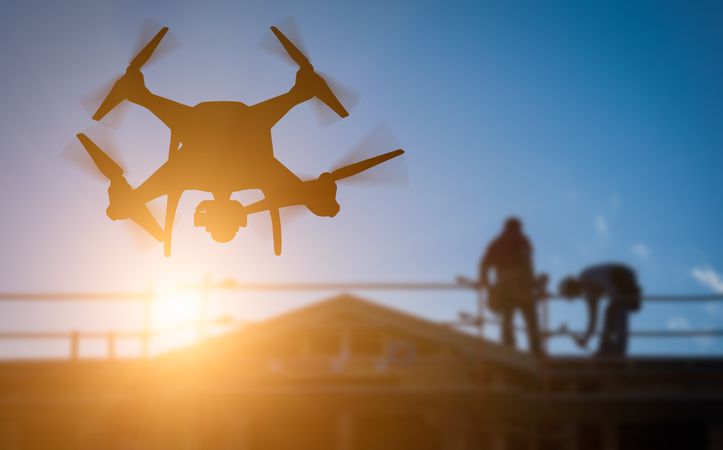 UAV Quadcopter Drone In The Air Over Building Under Construction.