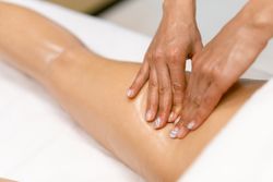 Masseuse giving a hamstring massage to a female with two hands